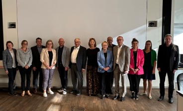 Gruppenbild der Mitglieder des Beirats vor einer weißen Wand.