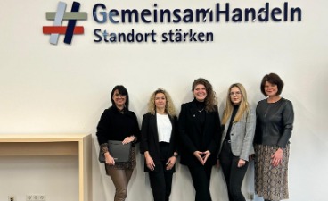 Vier Frauen, darunter Mitarbeiterinnen von KAUSA Nürnberg, stehen unter dem Schriftzug "Gemeinsam Handeln - Standort stärken".