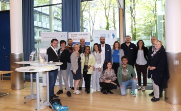 Abschluss Regionaltreffen München Eine Gruppe der Veranstalter steht nebeneinander im Foyer vor einem KAUSA Plakat